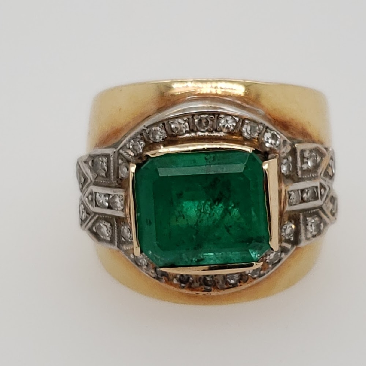 14K Two Tone Gold Emerald and Diamond Ring Size 6.75
Emerald is Emerald Cut and Bezel Set; wieghing approximately 6.02CT
It is surrounded by 27 Round Single Cut Diamonds; weighing approximately 0.80CTTW