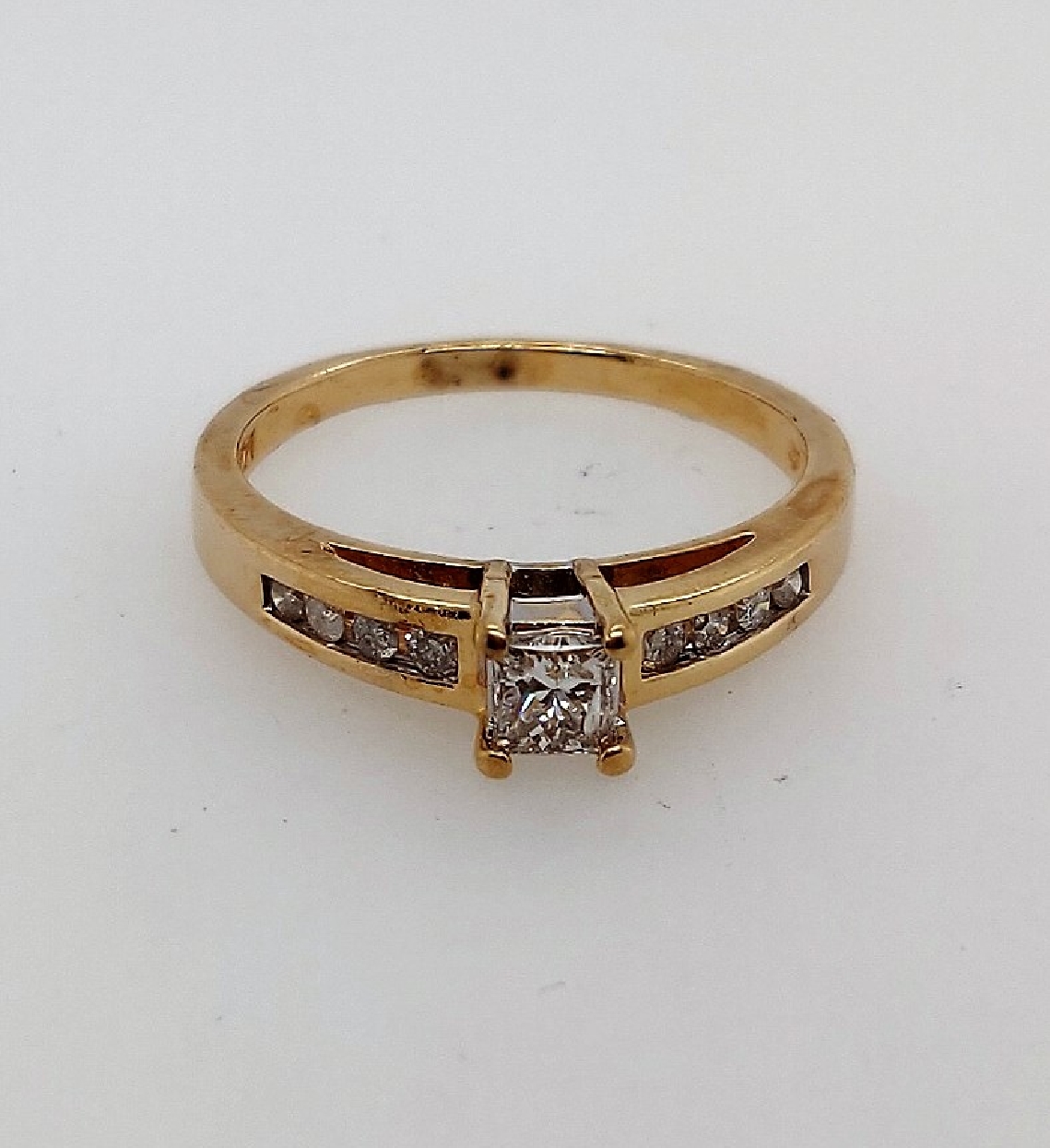 14kt yellow gold diamond engagement ring with prong set 0.28 princess cut dia center I1/J and eight channel set round diamonds approx 0.14 ctw sides I2/J. Size 8.5.
