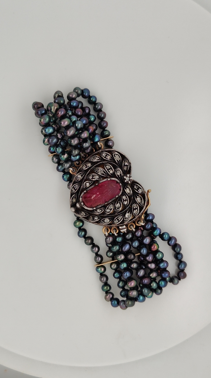 Five Strand Black Pearl Bracelet with 18K Yellow Gold and Silver Clasp. Carved Tourmaline and Diamond Clasp Dated to the Mid-Victorian Era.  

Seven inches total length. 