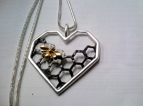 3773: One ladies Fashion Jewellery 30 inch snake chain with a heart shaped frame with a gnmetal honey combe and a gold honey bee.